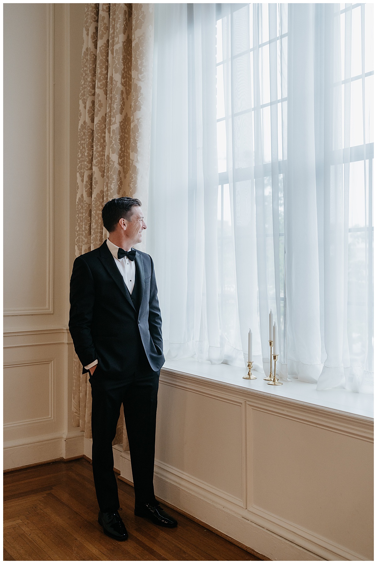 groom looks out window for Charlotte wedding photographer