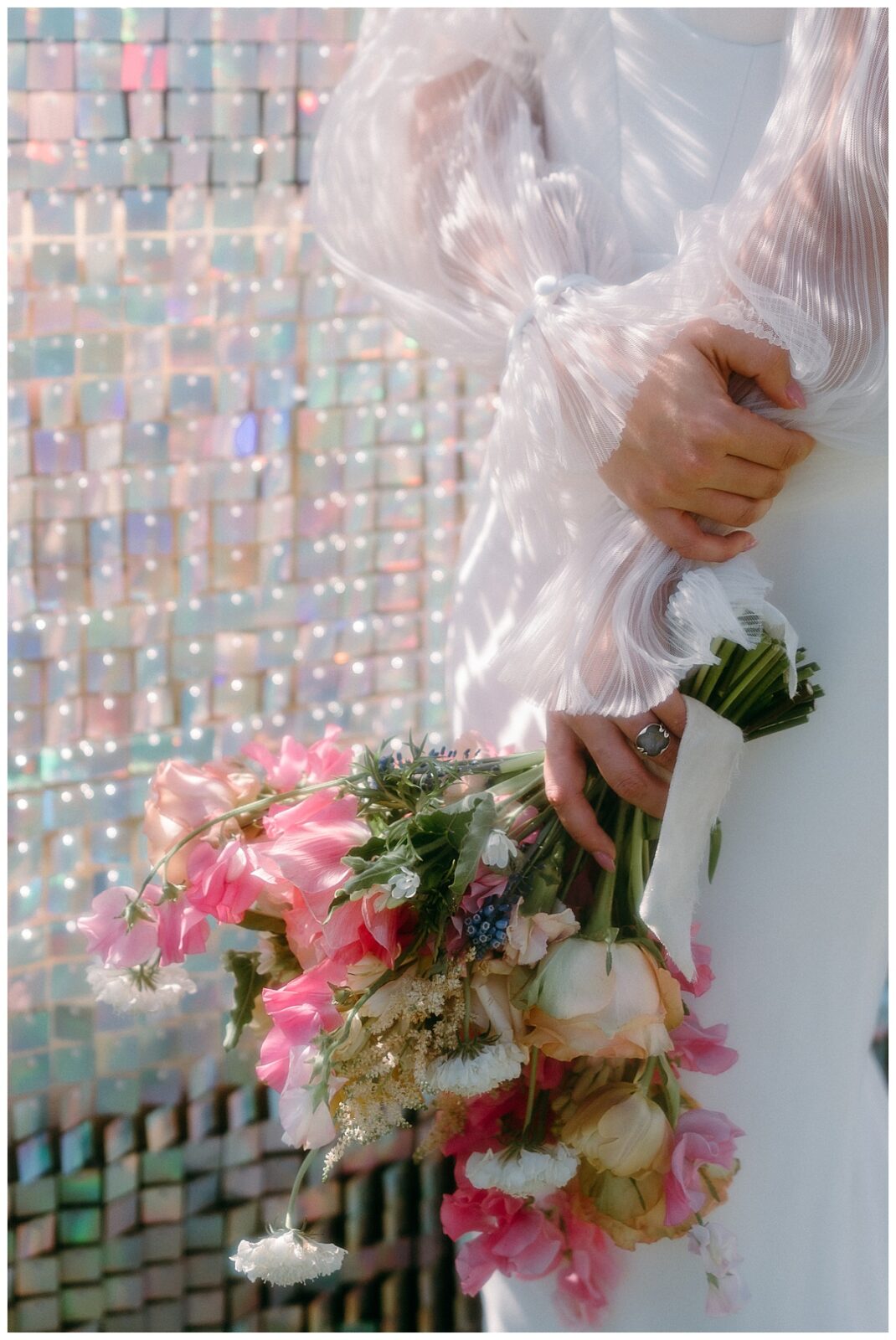bouquet is held in front of sequin backdrop by Charlotte wedding photographer