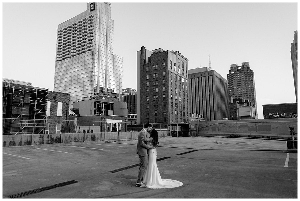 bride and groom kiss in city rooftop by North Carolina wedding photographer
