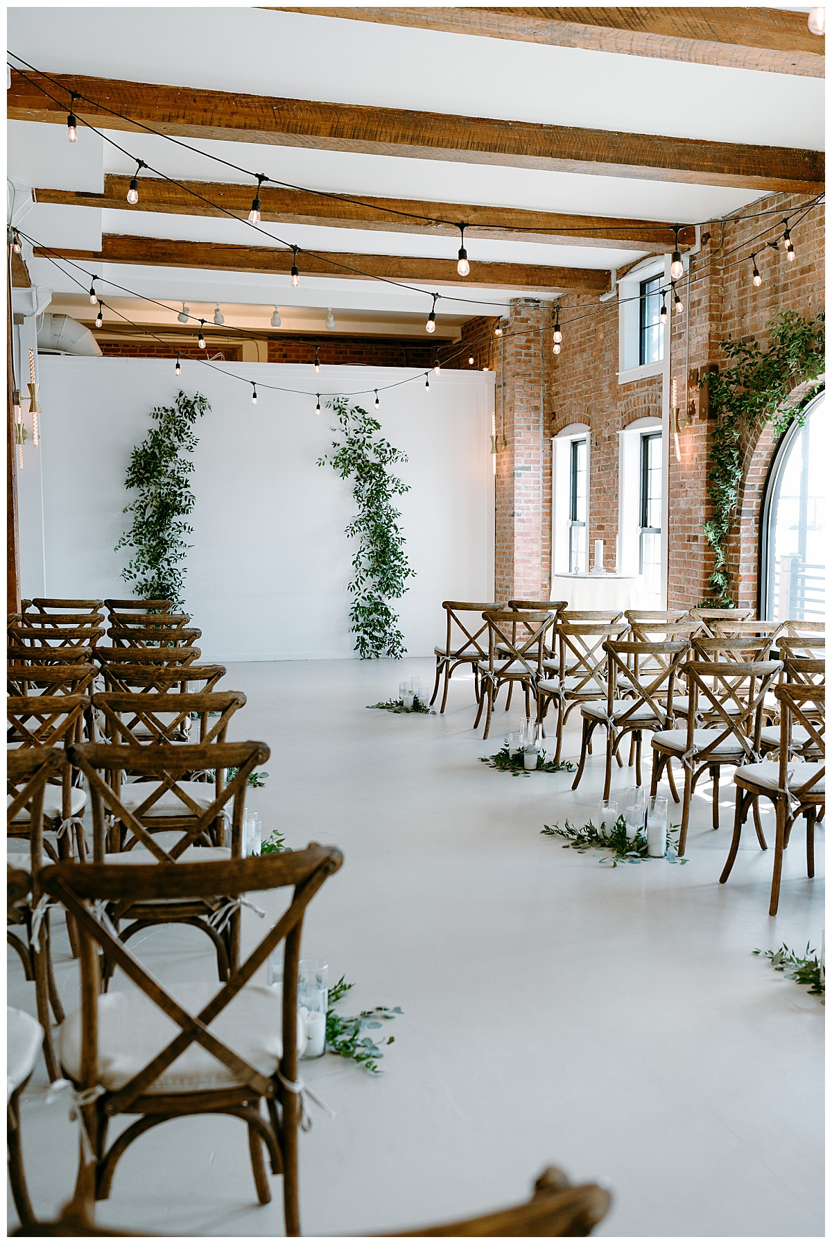 ceremony space is decorated with greenery arch and candles by The Hazel Club