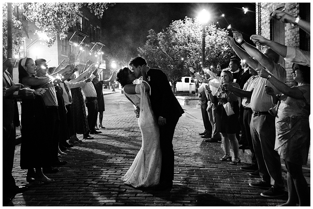 newlyweds kiss as guests hold out sparklers by North Carolina wedding photographer