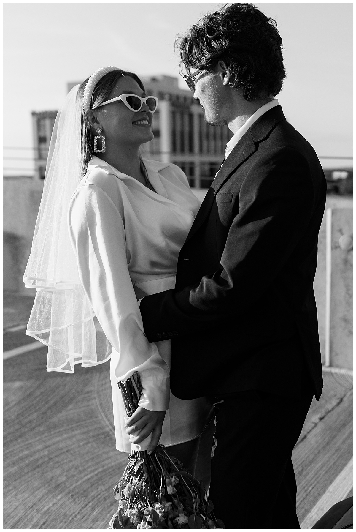 man and woman look at each other while wearing sunglasses by Charlotte engagement photographer