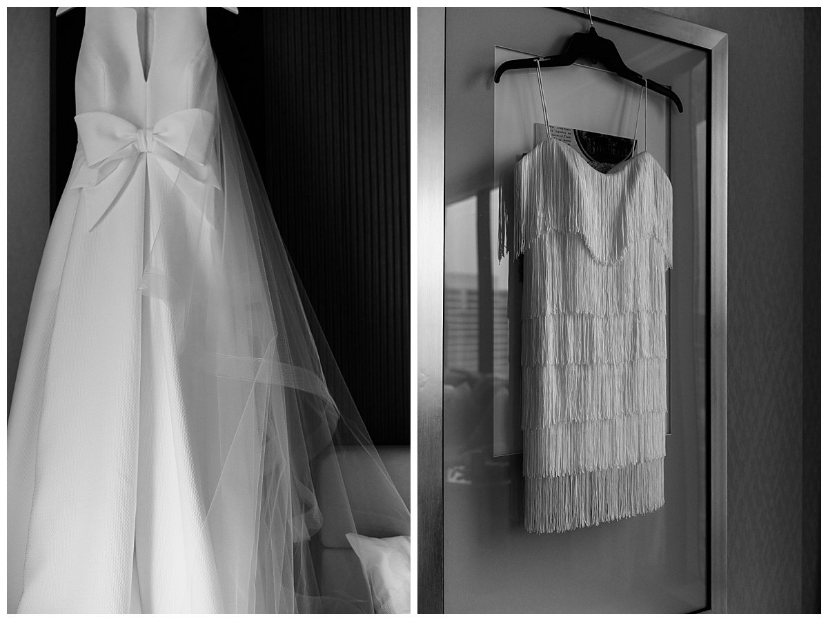 two wedding gowns hang in hotel room by The Hazel Club